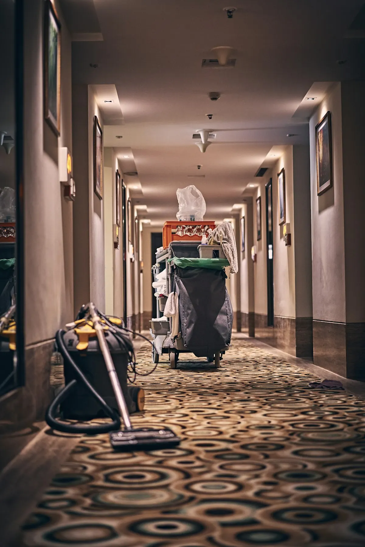 Housekeeping cart with supplies and a vacuum in a hotel corridor