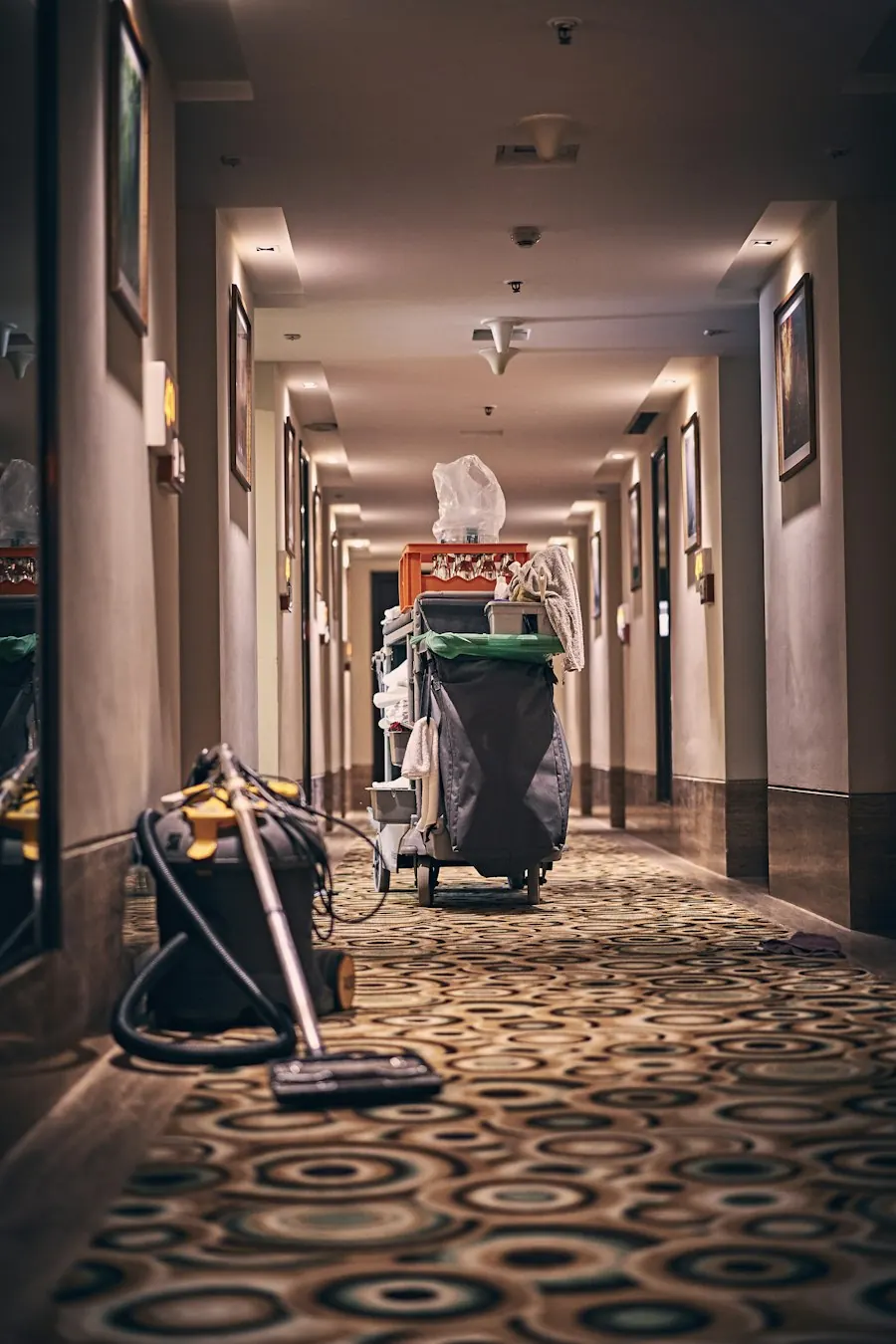 Housekeeping cart with supplies and a vacuum in a hotel corridor