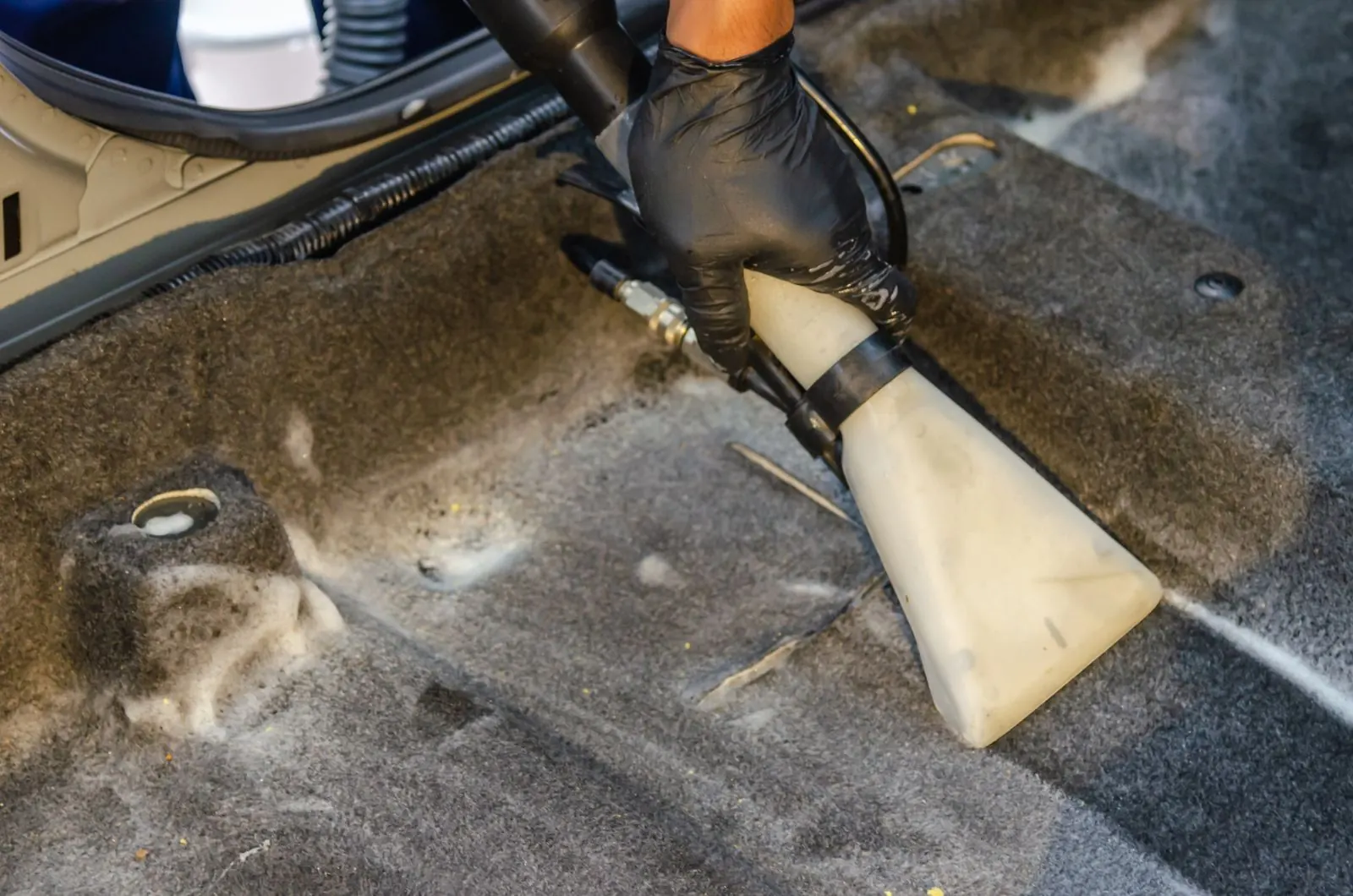 Gloved hand using an extraction nozzle on a carpet stain